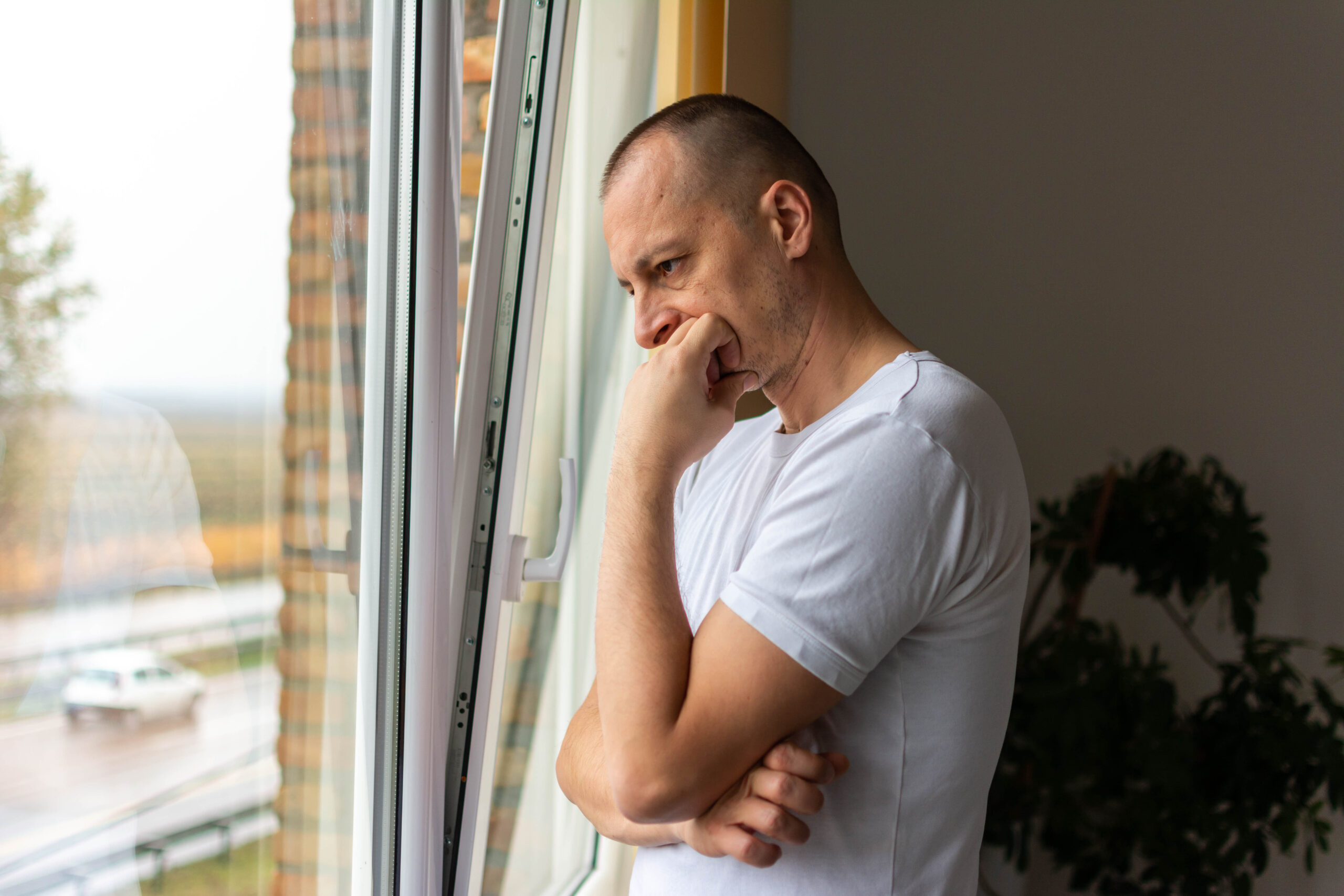 thoughtful entrepreneur leaning against a glass window in his office