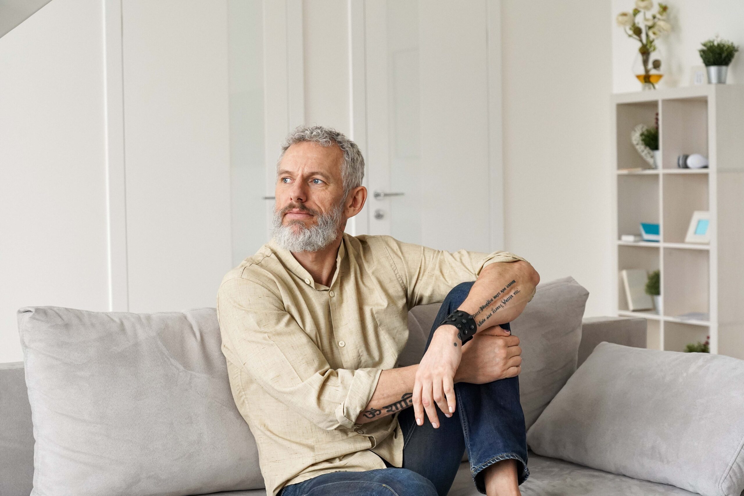 relaxed mature thoughtful man relaxing sitting on sofa and thinking at home.