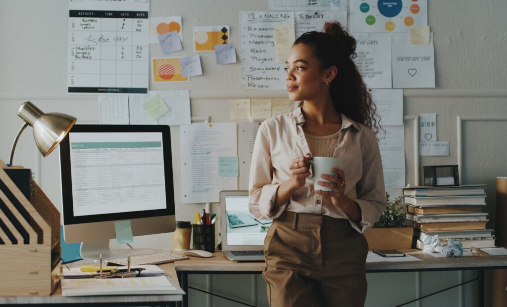 shot of an attractive young businesswoman standing and looking contemplative while holding a cup of coffee in her home office